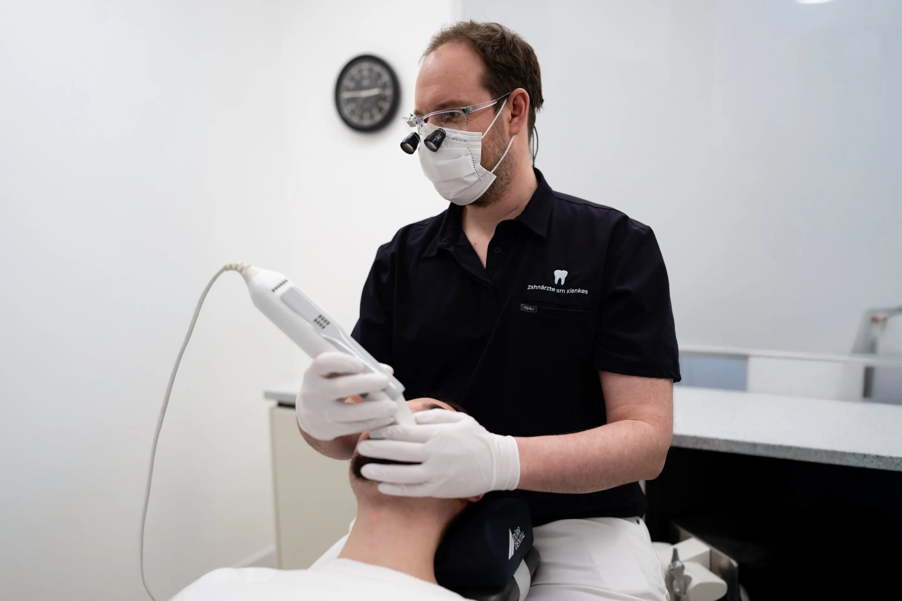 Zahnarzt führt bei einer Patientin einen digitalen 3D-Scan mit dem Intraoralscanner durch